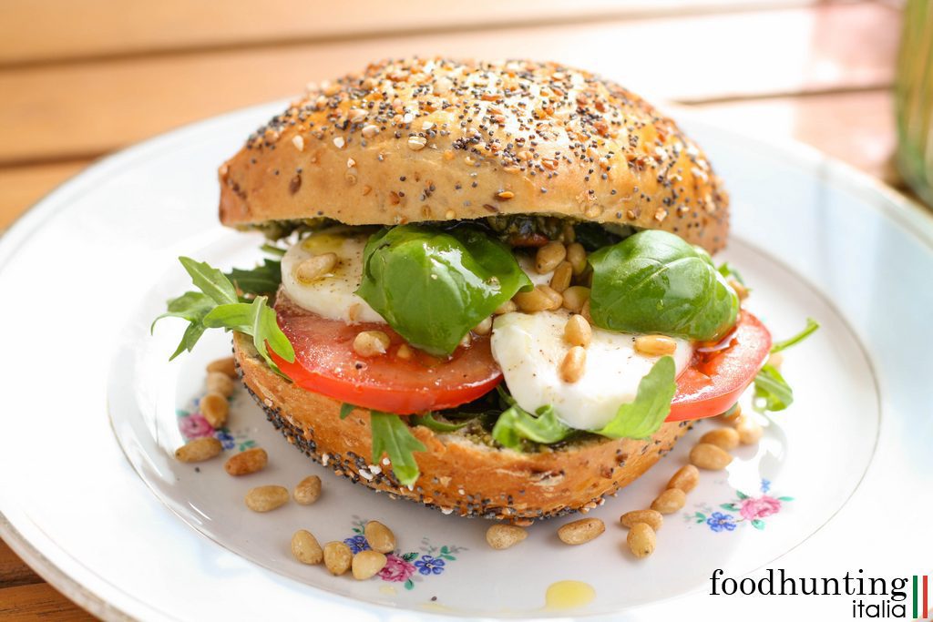 Een zomers broodje Caprese met mozzarella, tomaat, basilicum, rucola en pijnboompitten